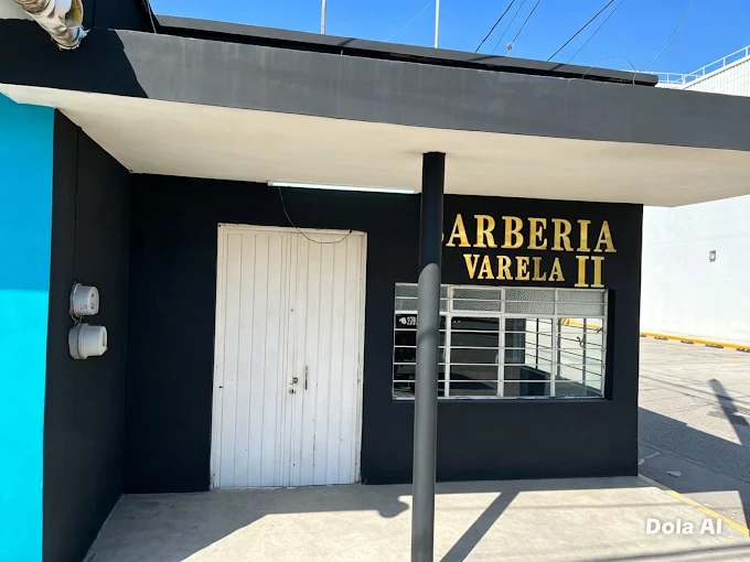Fachada de Barbería Varela 2, con letrero dorado sobre muro oscuro